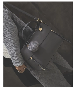 Detail of dark grey tote bag with gold hardware, plush pompom and adjustable strap