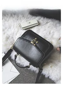 Detail of black vintage PU leather handbag featuring a retro gold buckle and textured finish
