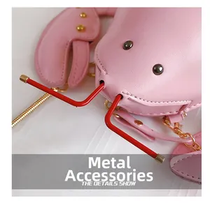 Detail of lobster-shaped crossbody bag featuring golden rivets and pink leather texture