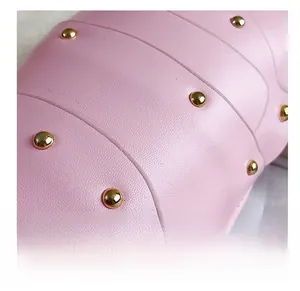 Detailed close-up of pink leather texture and golden round rivets on the crossbody bag