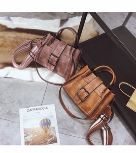 Detail of vintage matte leather handbags with striped straps and metal square buckles