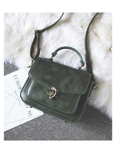 Close-up of vintage dark green PU leather bag with antique bronze buckle and strap