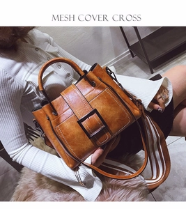 Close-up of vintage brown leather bag featuring large buckle and striped canvas strap