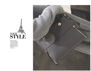 Detailed view of grey leather tote with gold magnetic clasp and plush ball charm