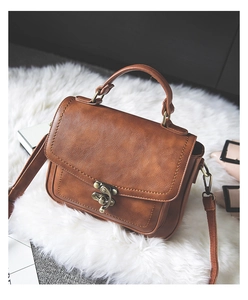 Detailed close-up of brown vintage PU leather handbag with antique bronze metal lock and handle