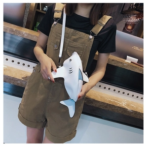 Detail of white PU leather shark-shaped crossbody bag worn across chest by a model
