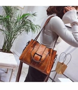 Detail of vintage brown textured leather handbag with contrast stitching and square buckle