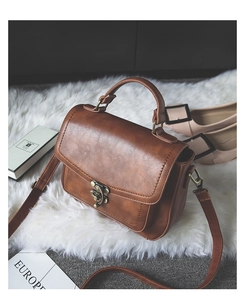 Close-up of vintage brown PU leather handbag with intricate floral hollow metal clasp