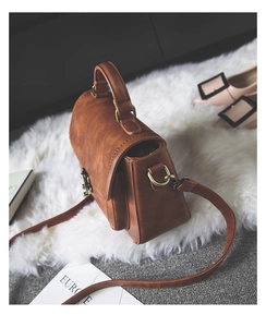 Detail view of brown PU leather handbag with vintage metal clasp and accordion side pleats