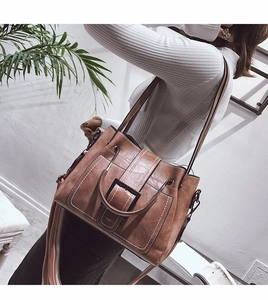 Detail of vintage matte leather crossbody bag featuring contrast stitching and wide striped strap