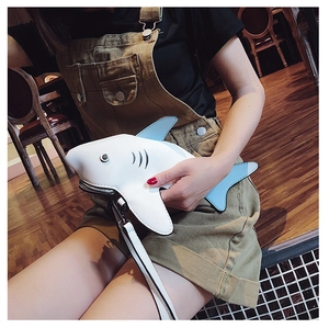 Detail view of a shark-shaped crossbody bag featuring blue and white leather patchwork