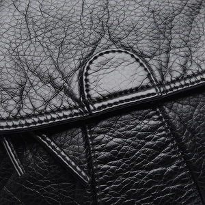 Close-up of black washed PU leather crossbody bag with pleated texture and fine stitching