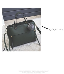 Detail view of dark green tote bag with side zippers, dual handles and a grey fur charm