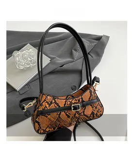 Close-up of snake skin texture bag with orange panel and gold metal buckle detail