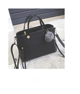 Detail of black pebbled leather tote bag with gold hardware and gray faux fur pompom