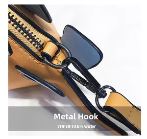 Detail of black metal hardware hook and zipper end on yellow crossbody dinosaur bag
