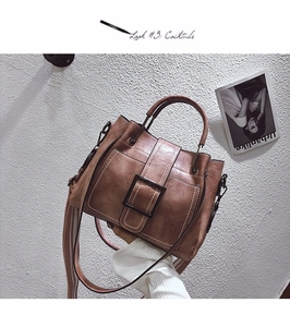 Close-up of vintage brown leather handbag with contrast stitching and large metal buckle