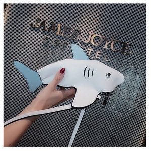 Close-up of funny shark-shaped crossbody bag with white leather and blue fins detail