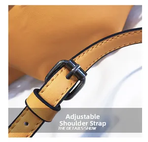 Detail of adjustable orange leather shoulder strap with dark metal buckle and black stitching