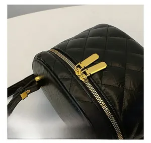 Close-up of quilted leather handbag featuring smooth gold dual zippers and black handle