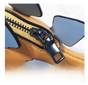 Close-up of a high-quality black metal zipper on a yellow dinosaur-shaped crossbody bag