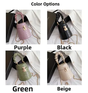 Detail view of four crocodile pattern bucket bags in purple, black, green and beige colors