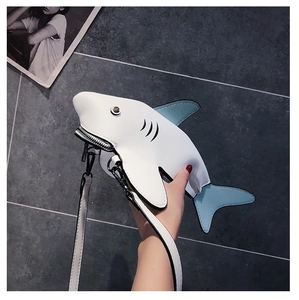Detail of shark-shaped crossbody bag featuring white PU leather and blue fin accents