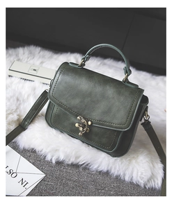 Detail of dark green vintage PU leather handbag with bronze metal lock on white faux fur