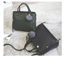 Detail of green and black leather tote bags with metal zippers and fluffy charms