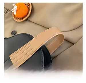 Detail shot of the contrast color handle with high-quality stitching on a leather bag