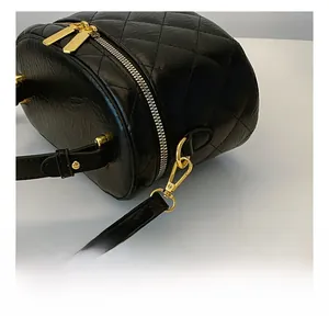 Detailed close-up of golden metal hooks and quilted leather texture on the black bucket bag