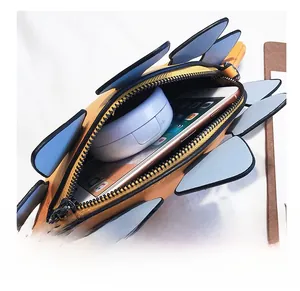 Detail showing the inner capacity of the dinosaur bag with a phone and compact case