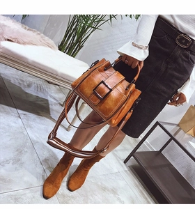 Close-up of brown frosted leather bucket bag with retro buckle and suede boots