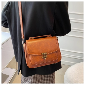 Detail of vintage brown PU leather handbag with antique metal lock and textured surface