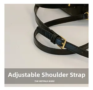 Detail of adjustable black leather shoulder strap with gold-tone buckle for handbag