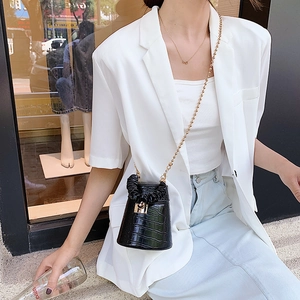 Detail of black faux leather bucket bag with crocodile texture and gold chain strap