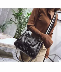 Detail of black leather crossbody bag featuring white stitching and striped wide strap