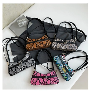 Flat lay of colorful snakeskin baguette bags in five stylish shades on a white surface