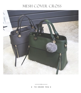 Detail of green and gray tote bags with gold hardware and fluffy ball charm on plush rug
