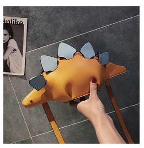 Detail of yellow dinosaur dinosaur crossbody bag with blue fins and smooth PU leather