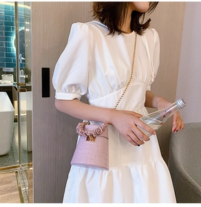 Detailed close-up of pink faux crocodile bucket bag with pleated handle and gold chain strap