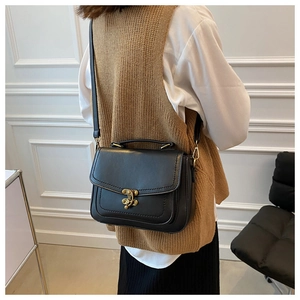 Detail of vintage black PU leather crossbody bag with gold buckle and adjustable strap
