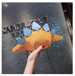 Detail of yellow dinosaur crossbody bag with blue scales and long shoulder strap