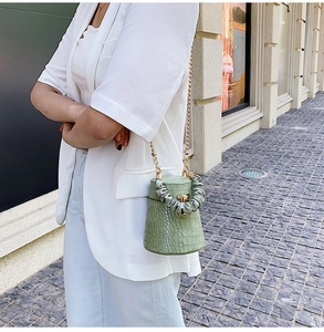 Detail of mint green crocodile pattern bucket bag with gold chain and pleated handle
