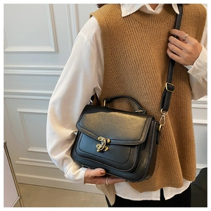 Detail of vintage black PU leather crossbody bag with antique gold buckle on model