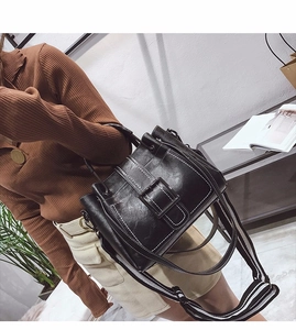 Detail of black vintage crossbody bag showing contrast white stitching and square buckle