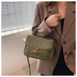 Detail of dark green vintage PU leather crossbody bag with antique bronze metal lock