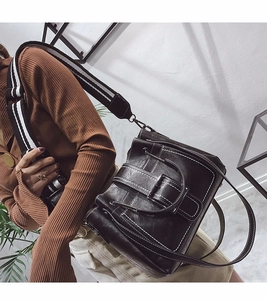 Fashionable black vintage bucket bag worn by model with striped shoulder strap