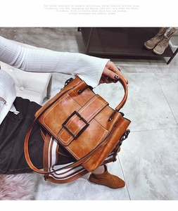 Detail of caramel vintage leather bag with striped strap and large square buckle