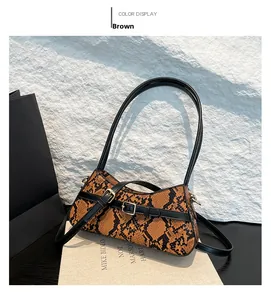 Detail of brown snakeskin texture and black belt strap buckle on fashionable crossbody bag